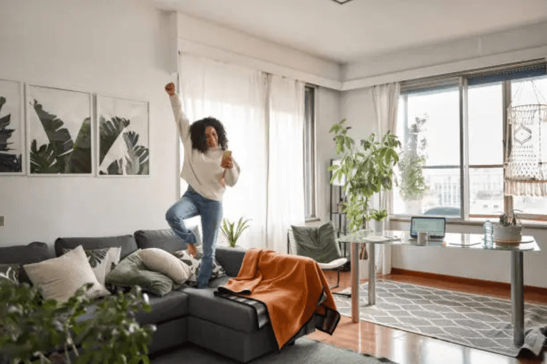 woman dancing on a couch in a bright apartment living room