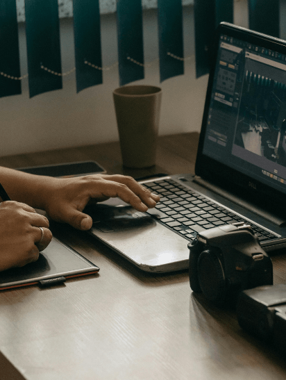 person working on a laptop with a camera nearby