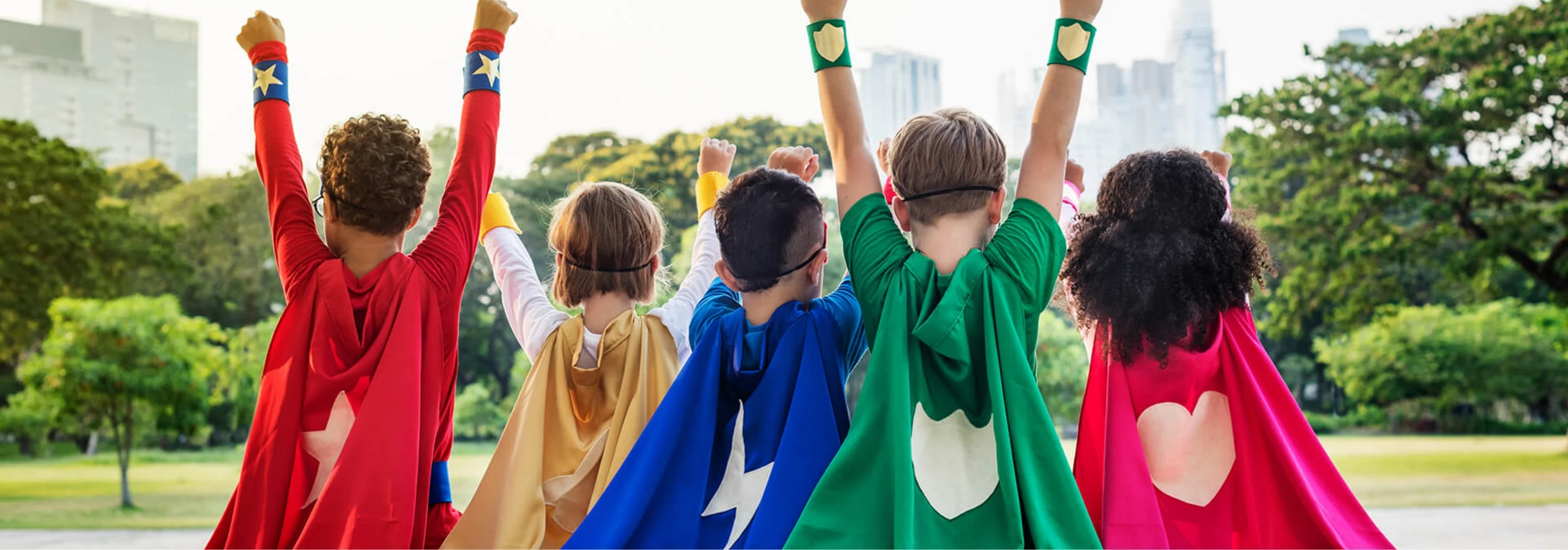 children in colorful superhero costumes at a park